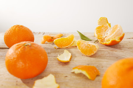 oranges on a wooden table. citruses with peeled peel and slices on a light background. fruit under sunlightの写真素材