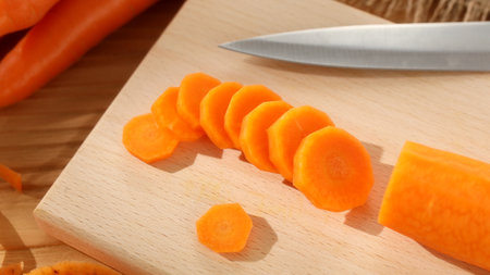 preparing fresh vegetables. cutting carrots on a cutting board. healthly food. sunny day.の写真素材