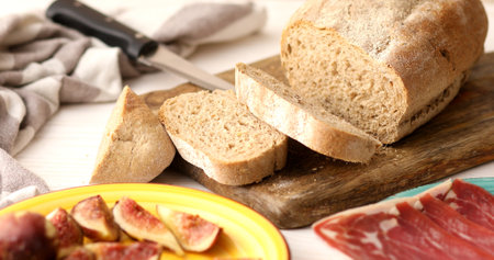 Bread with a knife on a cutting board. Slices of bread for making a sandwich with prosciutto and...