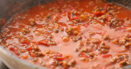 Minced meat and tomato sauce are boiled in a frying pan. Hot steam and bubbles. Cooking bolognese sauce. Food preparation in the kitchen. A series of photos to visualize the recipe.の写真素材