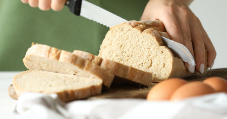 A young woman cuts bread in the kitchen. Slices of bread on a cutting board. Cooking food. A series...