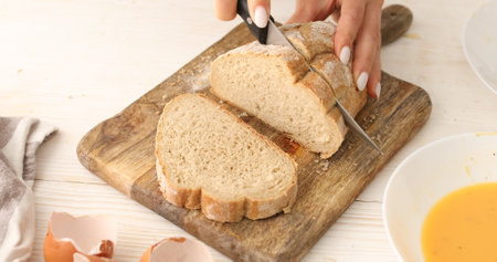A young woman cuts bread in the kitchen. Slices of bread on a cutting board. Cooking food. A series...