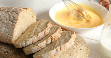Beating eggs and milk with a whisk in a plate. Slices of bread on a cutting board. Cooking food. A series of photos of Bread with Egg Recipe. Dolly shot.の写真素材