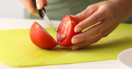 Red Tomato is cut into small pieces on a cutting board. Close-up. Preparing vegetable salad. Healthly food.の写真素材