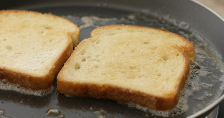 The bread is fried in butter or oil in a frying pan. Making croutons. Cooking food. Preparing...