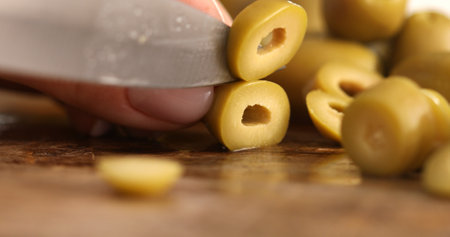 Female hands cut green olives into rings on a cutting board. Healthy meal, vegetarian food. Pickled vegetables snack. Dolly shot. Mediterranean organic fresh food ingredient for salads.の写真素材