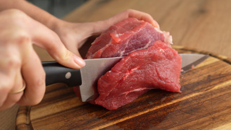 Close-up shot of Slicing Raw Beef on Cutting Board.の写真素材