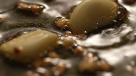 Garlic sizzling in oil in a pan. Step of Recipe Fried Assassins Spaghetti Cooking. Close-up, shallow...