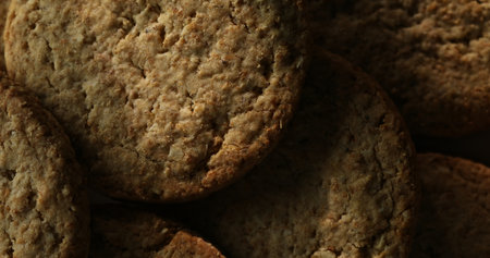 A close-up shot of rustic cookies highlighting their rough, textured surface. The warm light and shadow play enhance the natural grain and artisanal feel.の写真素材