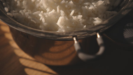 Cooked white rice in metal pot on wooden surfaceの写真素材