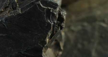 Close-up of dark fractured stone with curved edges and layered rock faceの写真素材