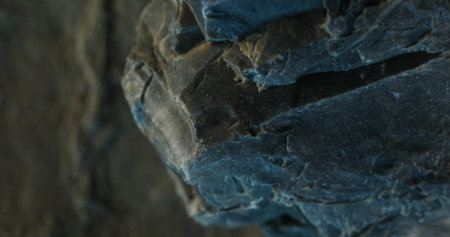 Close-up of dark slate rock with jagged edge and soft bluish shadowsの写真素材
