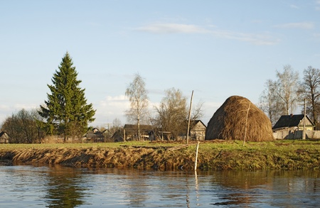 Village on the bank of the spring river - houses, a fur-tree, a haystackの写真素材