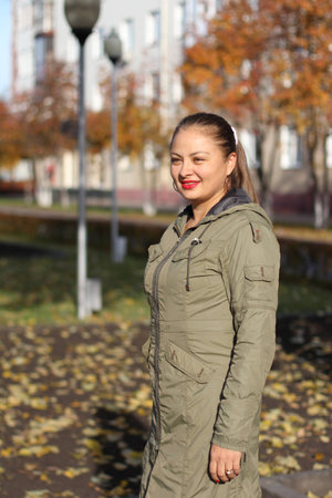 round-faced young cheerful woman walking on the street in the autumn on a sunny dayの写真素材