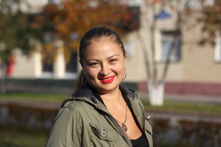 round-faced young cheerful woman walking on the street in the autumn on a sunny dayの写真素材