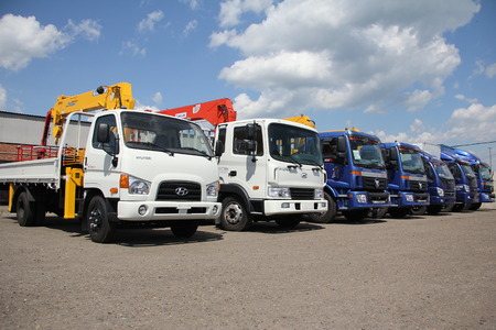 White Hyundai, blue foton flatbed trucks with yellow crane arm is in the parking lot - Russia, Moscow, 30 August 2016のeditorial素材