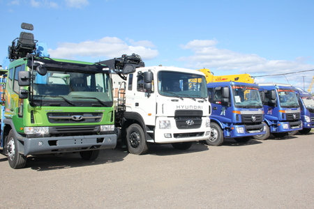 White, blue, green flatbed trucks with yellow crane arm is in the parking lot - Russia, Moscow, 30 August 2016のeditorial素材
