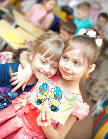 portrait of a cheerful smiling girl holding a bright colorful picture of butterfly painted colors, plasticine and crayons in kindergarten - Moscow, Russia - February 4, 2016のeditorial素材