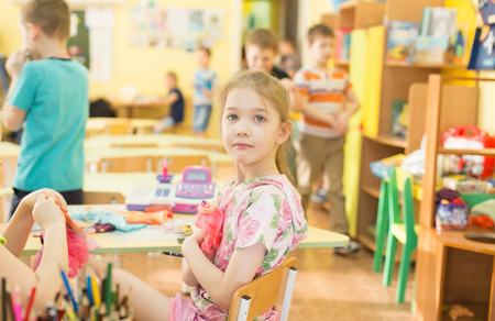 portrait of a cheerful smiling girl holding a bright colorful doll toy in kindergarten - Moscow, Russia - February 4, 2016のeditorial素材