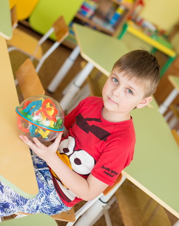 portrait of a cheerful smiling boy holding a bright colorful ball maze toy in kindergarten - Moscow, Russia - February 4, 2016のeditorial素材