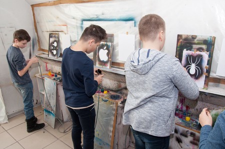 a group of children of teenagers engaged in airbrushing paint brightly colored pictures in a artistical studio - Russia, Moscow - January 24, 2016のeditorial素材