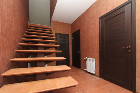 An Open staircase with stone steps going up to the inside corridor rooms close-up on a background of bright walls and dark doorsの写真素材