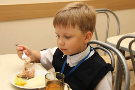 merry schoolboy Sitting At Table In School Cafeteria Eating Meal. drinking juice - Russia, Moscow, the first High School, the first class b - September 30 2017のeditorial素材