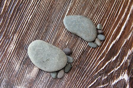stones lie in the shape of a foot with five fingers on a wooden table macro photographyの写真素材