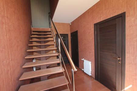 An Open stairs with stone steps going up to the inside corridor rooms, offices close-up on a background of bright walls and dark doorsの写真素材