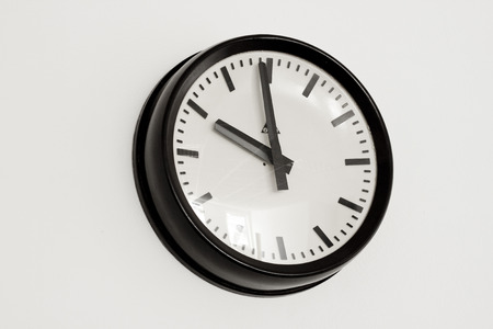 Old metal wall clock on white wall