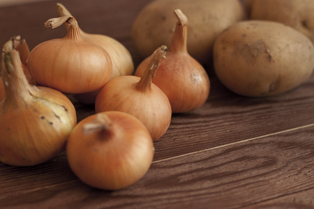 Potatoes and onions on a wooden boardの写真素材