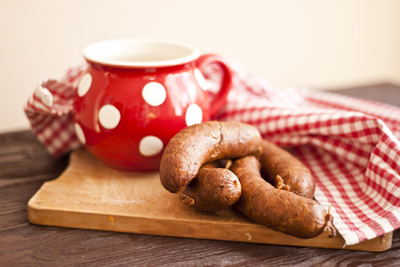 Raw sausages on board and red mug with polka dots