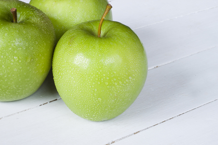 Close-up of green beautiful apple isolated on white wooden deskの写真素材