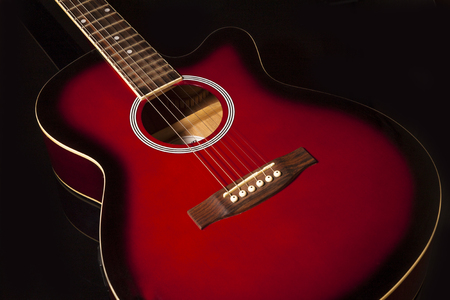 acoustic guitar in red on a black backgroundの写真素材