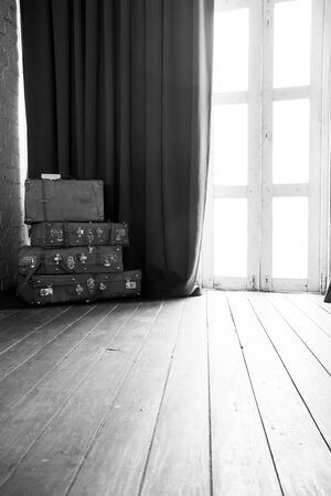 The room has an empty leather bag near the curtains and has light from the glass door in black and white tone.の写真素材