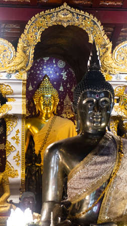 Two Buddha images, black and gold, are in the temple because people come to pay their respects.の写真素材