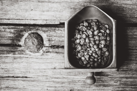 Top view of coffee beans on Coffee grinder tray, wood background, Colour B&W retro styleの写真素材