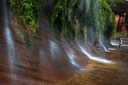 traveller with waterfall landscape  in tropical Rainforest , slow shutter speed to blur the water,Thailandの写真素材