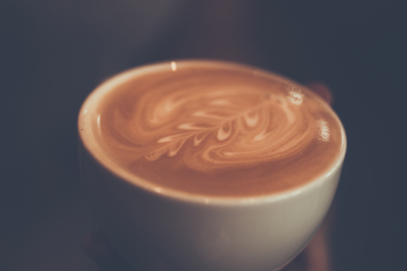A cup of coffee with fern pattern in a white cup hand holding, vintage color ,Thailandの写真素材