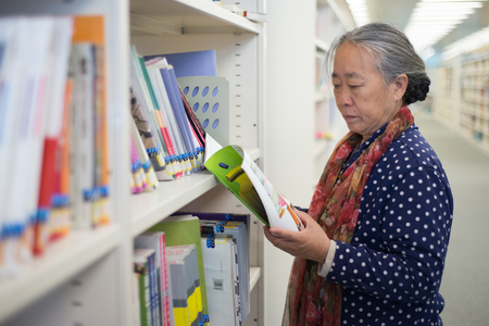 Old lady reading and studying in the library