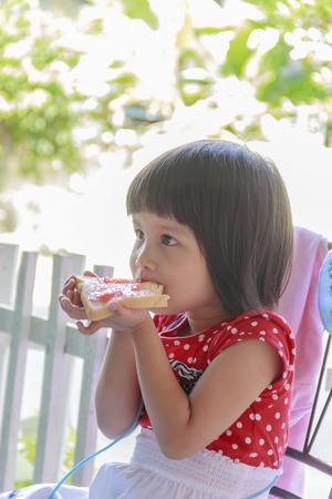 Happy little toddler girl enjoying healthy breakfast eatingの写真素材