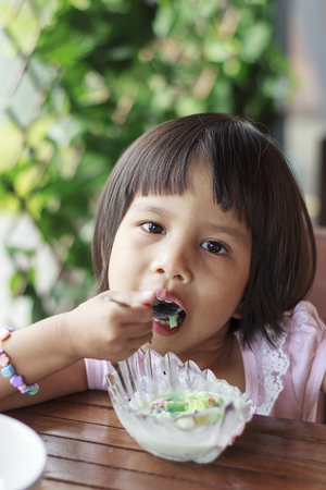 Cute Toddler Girl Eating Ice-Cream on a spoonの写真素材