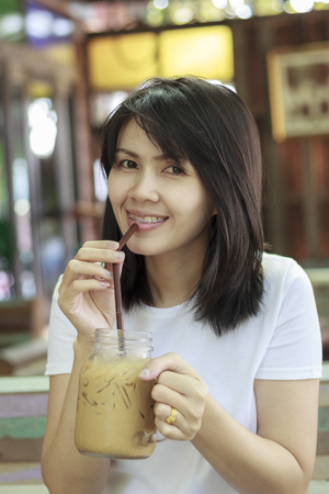 woman is drinking coffee via brown strawの写真素材