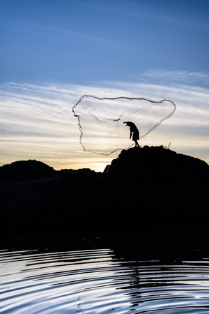 fisherman standing on the rock  in action when fishingの写真素材