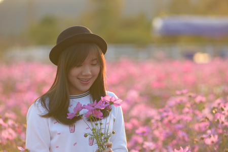 Beautiful Asian girl smiling in pink cosmos flower fieldの写真素材