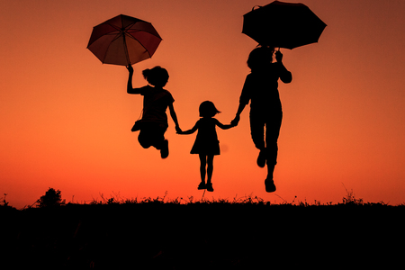 silhouette of a family with umbrella in hand  in the countryside at sunset (Motion Blur)の写真素材