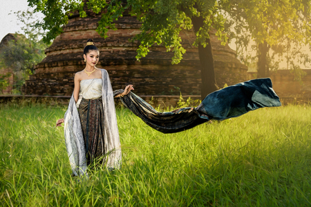 portrait of beautiful Thai girl in tradition dress with beautiful sunlight and pagoda background in temple of Ayutthaya Thailand (with oilpaint filter)の写真素材