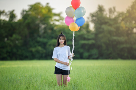 girl with balloons in the green field. Smiling girl play with balloons happilyの写真素材