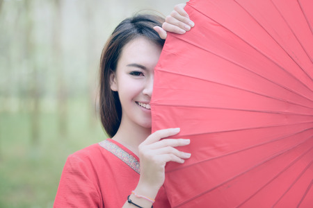 portrait of beautiful girl in red dress smiling with red umbrellaの写真素材