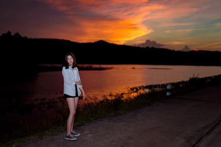 beautiful young woman standing on street with beautiful sky during sunsetの写真素材